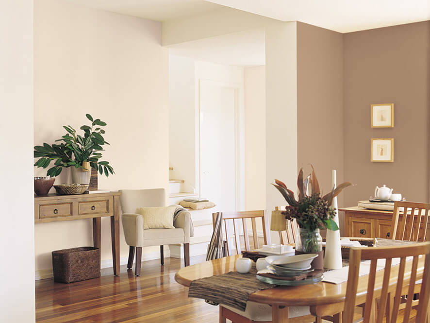 Neutral brown traditional dining setting with wooden floorboards and dining table and chairs plant